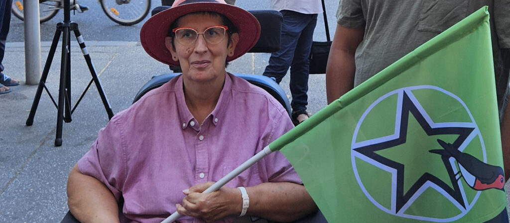 Photo d'Odile Maurin, portant le drapeau PEPS (vert avec une étoile dans un cercle et un rouge-gorge)