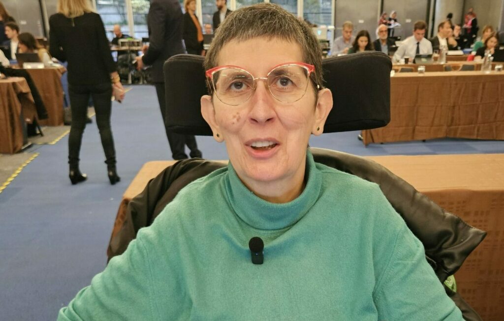 photo d'Odile Maurin dans son fauteuil roulant devant son ordinateur dans la salle du conseil métropolitain du 17 octobre 24