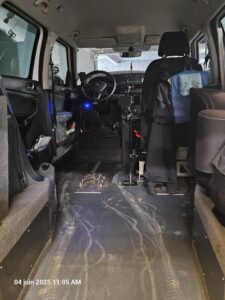 Intérieur de mon Skoda Yeti, avec l'emplacement pour accrocher au sol le fauteuil roulant, le volant dont je ne me sers pas, et à sa droite le joystick, et à droite le siège passager, vu depuis la rampe d'entrée à l'arrière. 